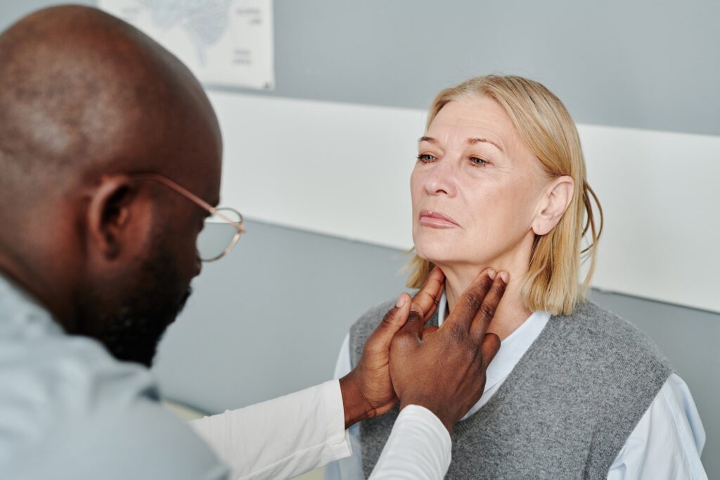 Mature blond female patient having checkup of her thyroid by endocrinologist